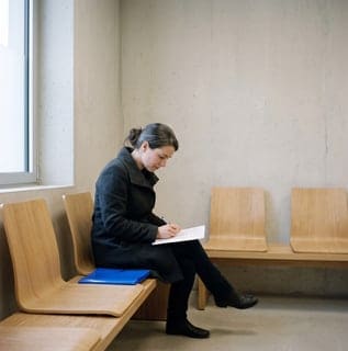 Una mujer rellena el formulario previo en la sala de espera